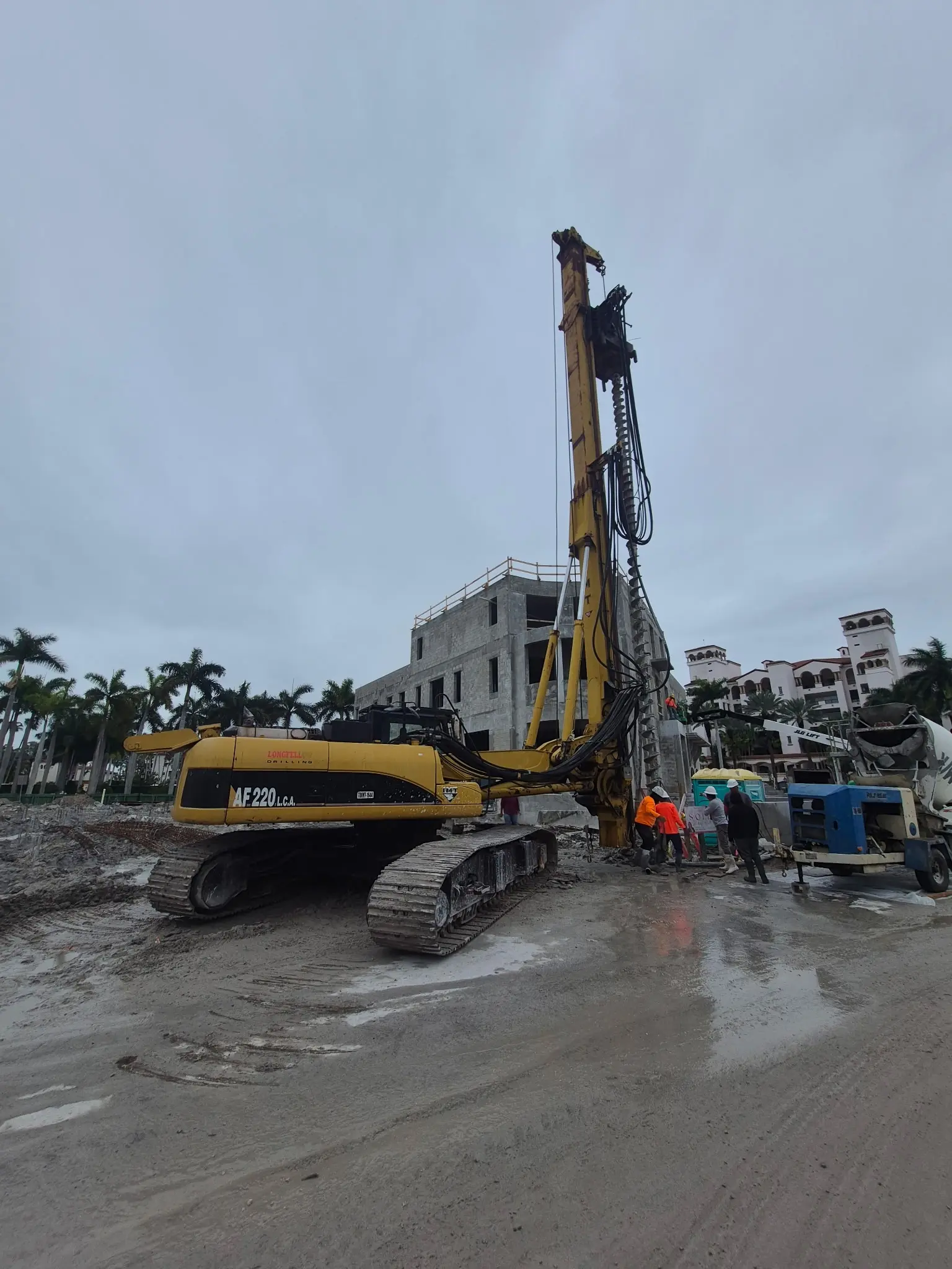 Auger drilling rig alongside a building under construction